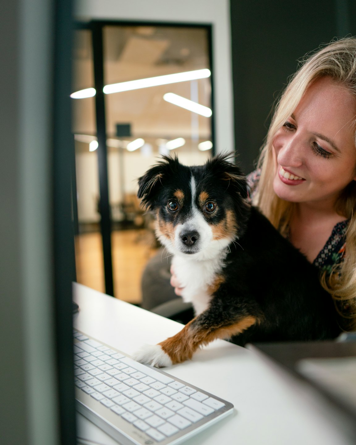 Woman and her dog look at a computer screen together.